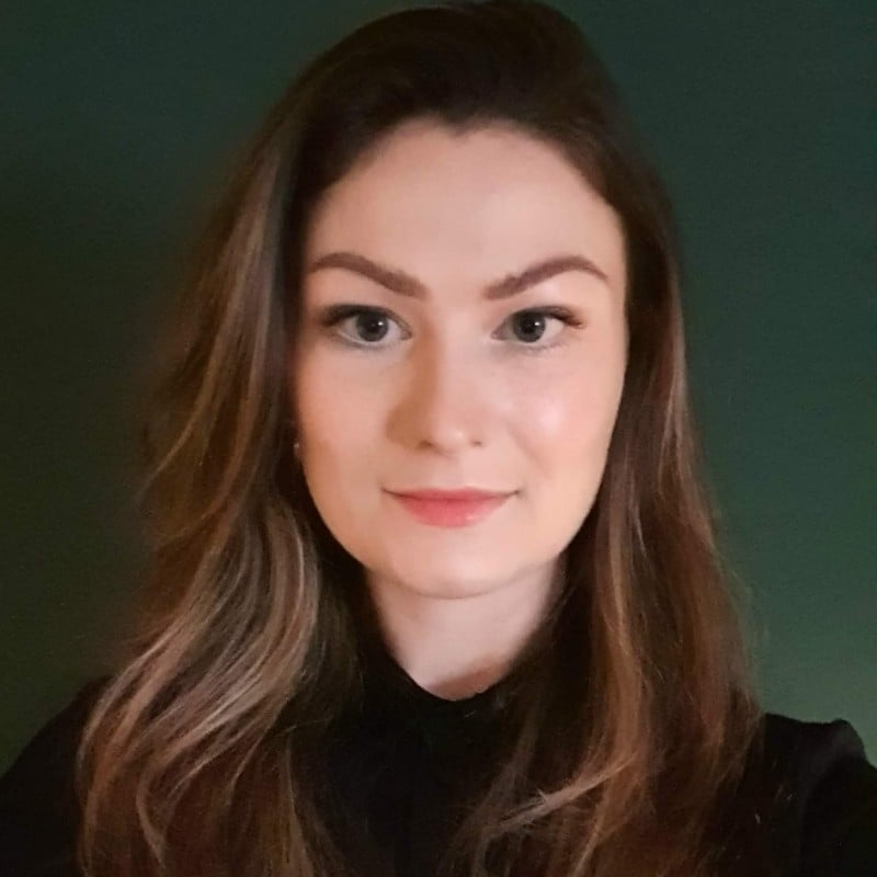 Woman with long hair, neutral expression.