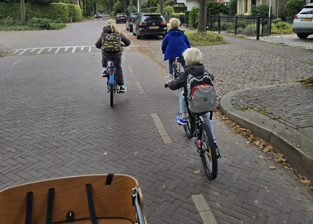 3 cycling children with backpacks